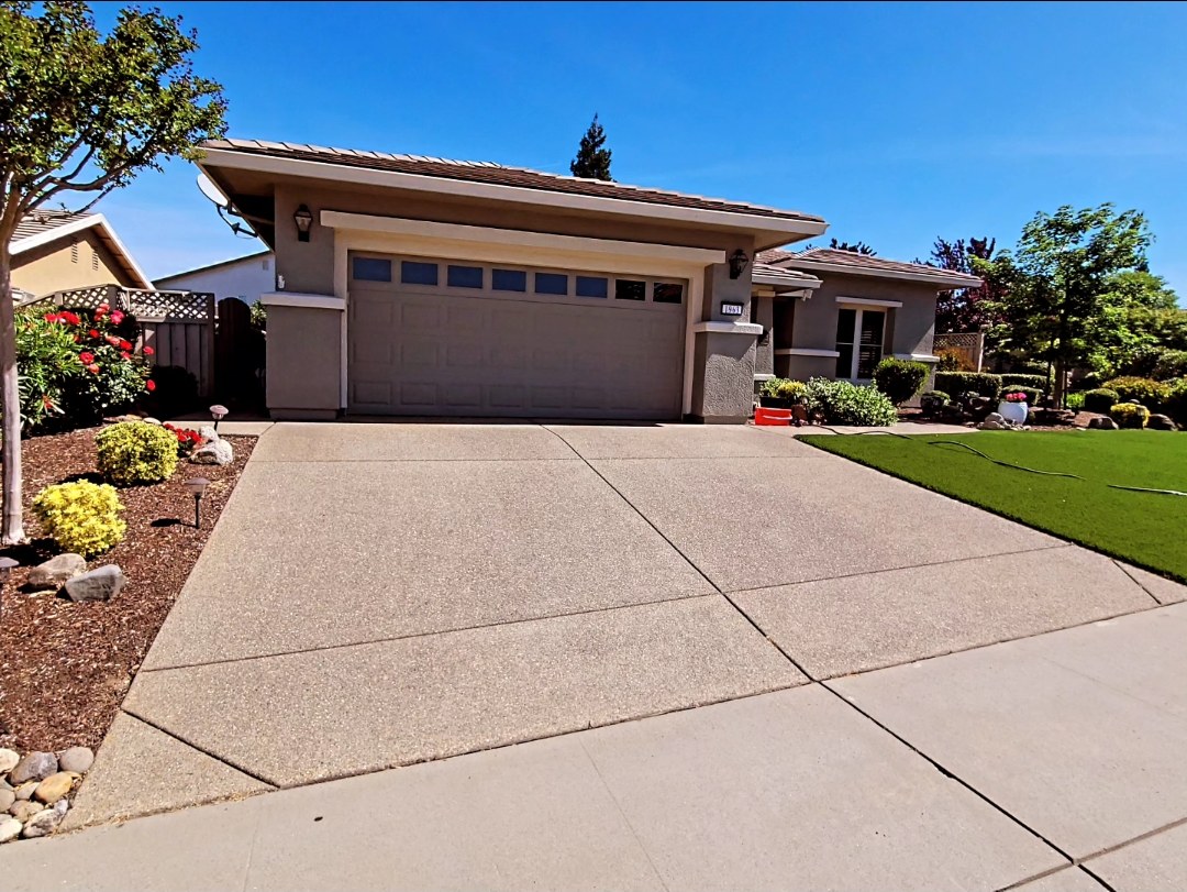 Clean concrete driveway outside a landscaped home